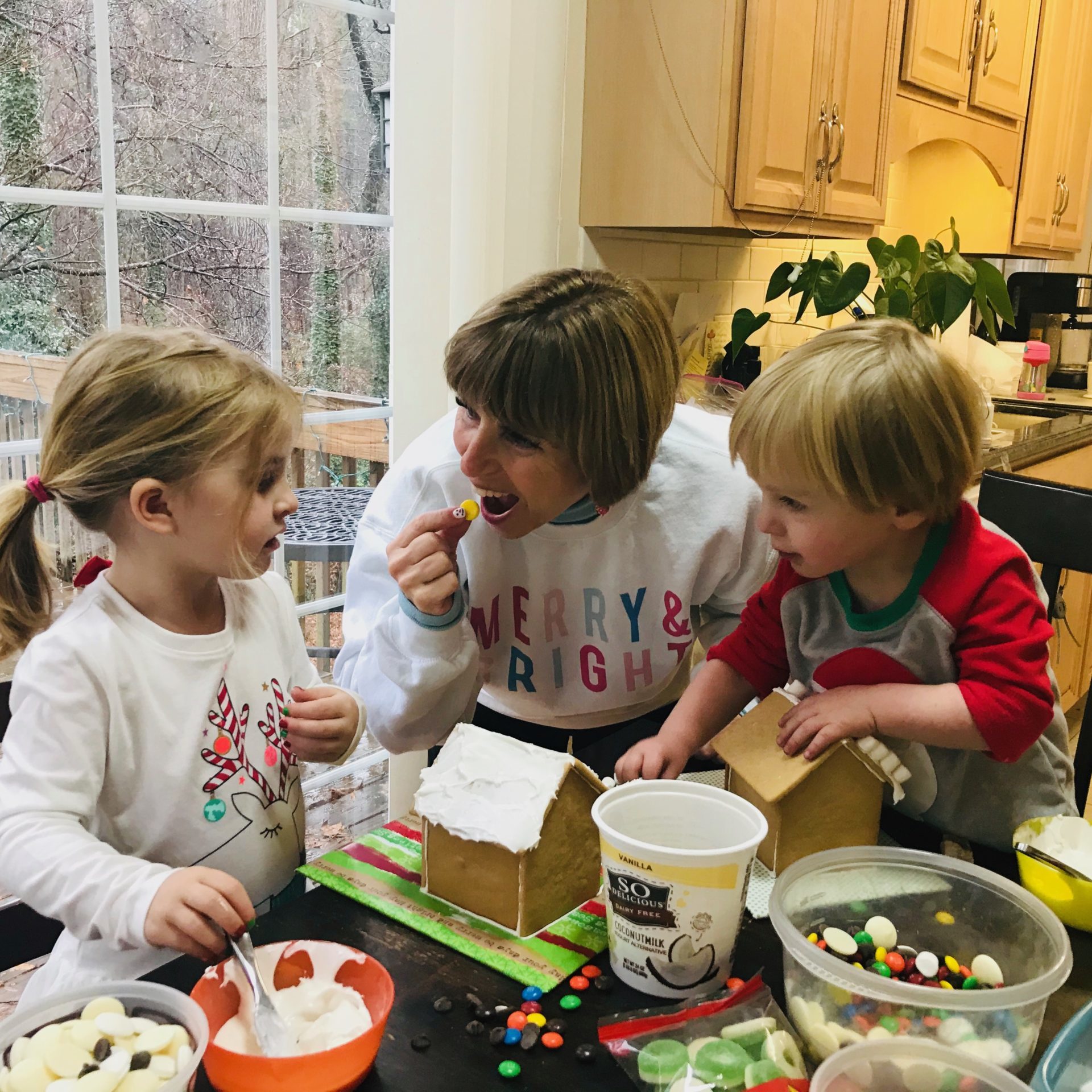 lady and two children decorating gingerbread houses